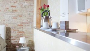 Una cocina con pared de ladrillo, una tetera, tazas y una caja con la etiqueta 'relax'.