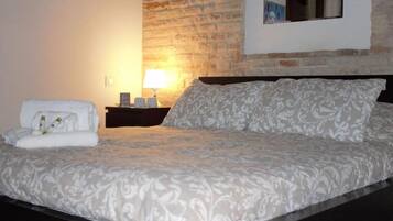 A neatly made bed with a patterned bedspread, a bedside lamp, and a towel on the side.