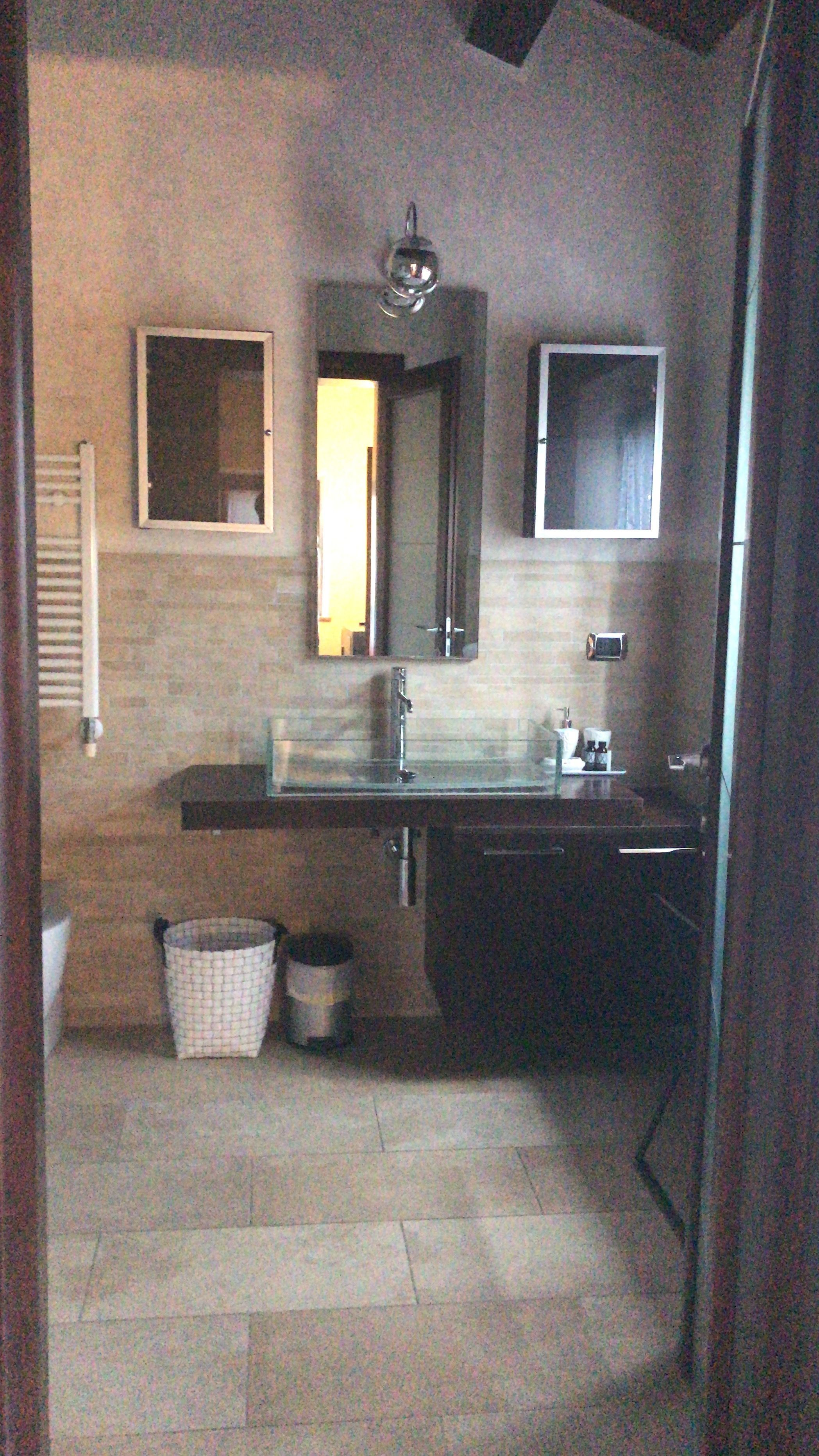 Un bagno con lavandino, specchio e portasciugamani.