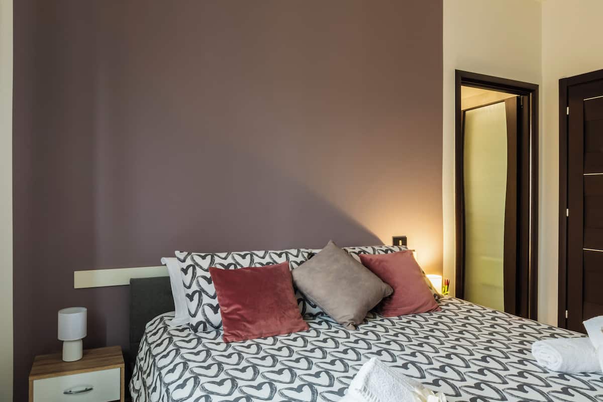 A hotel room with a bed, a nightstand, and a door.