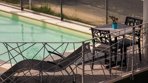 Un espace aménagé au bord de la piscine, avec une table et des chaises, un pot de fleurs et une vue sur la piscine.