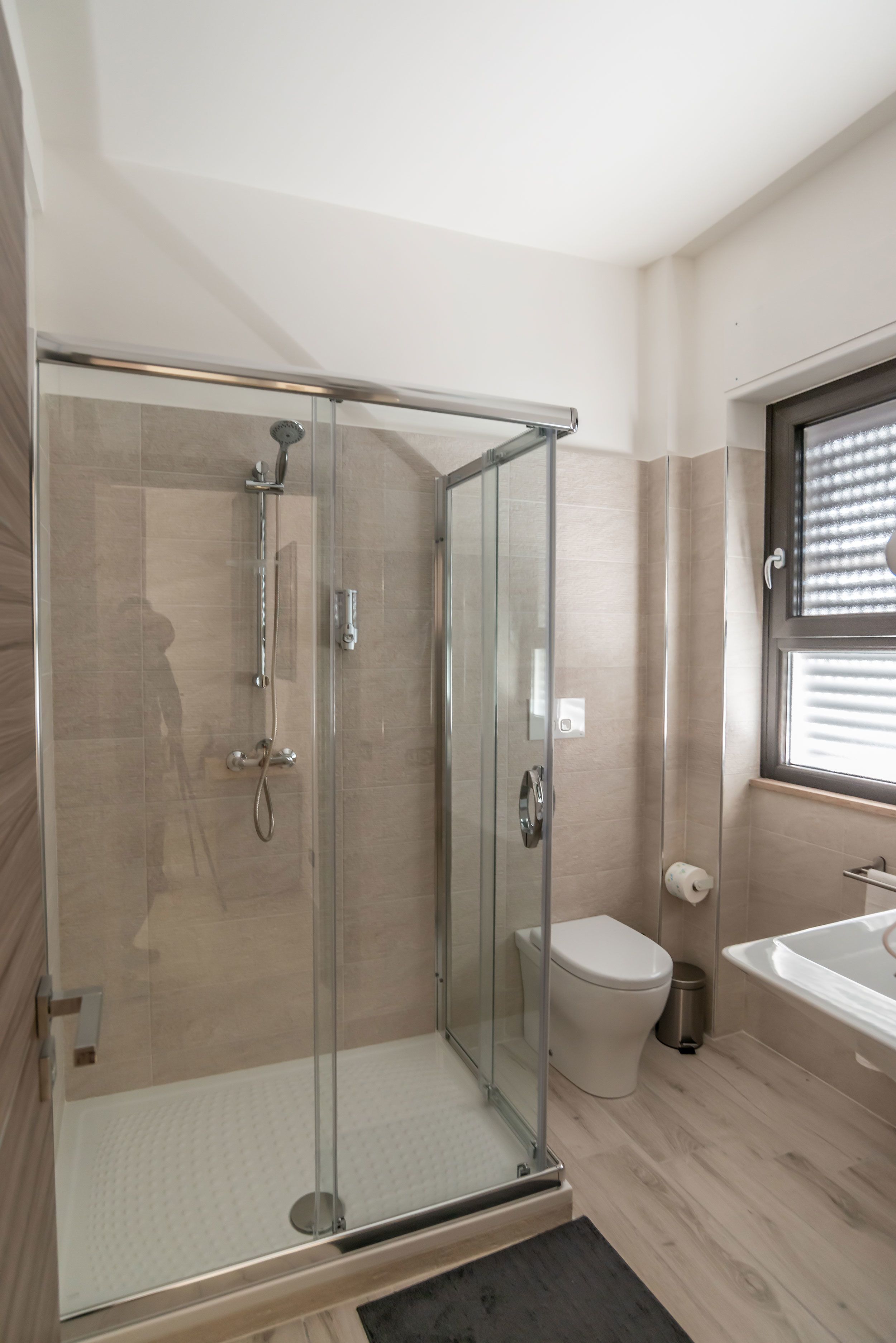 A modern bathroom with a glass-enclosed shower, a toilet, and a bathtub.