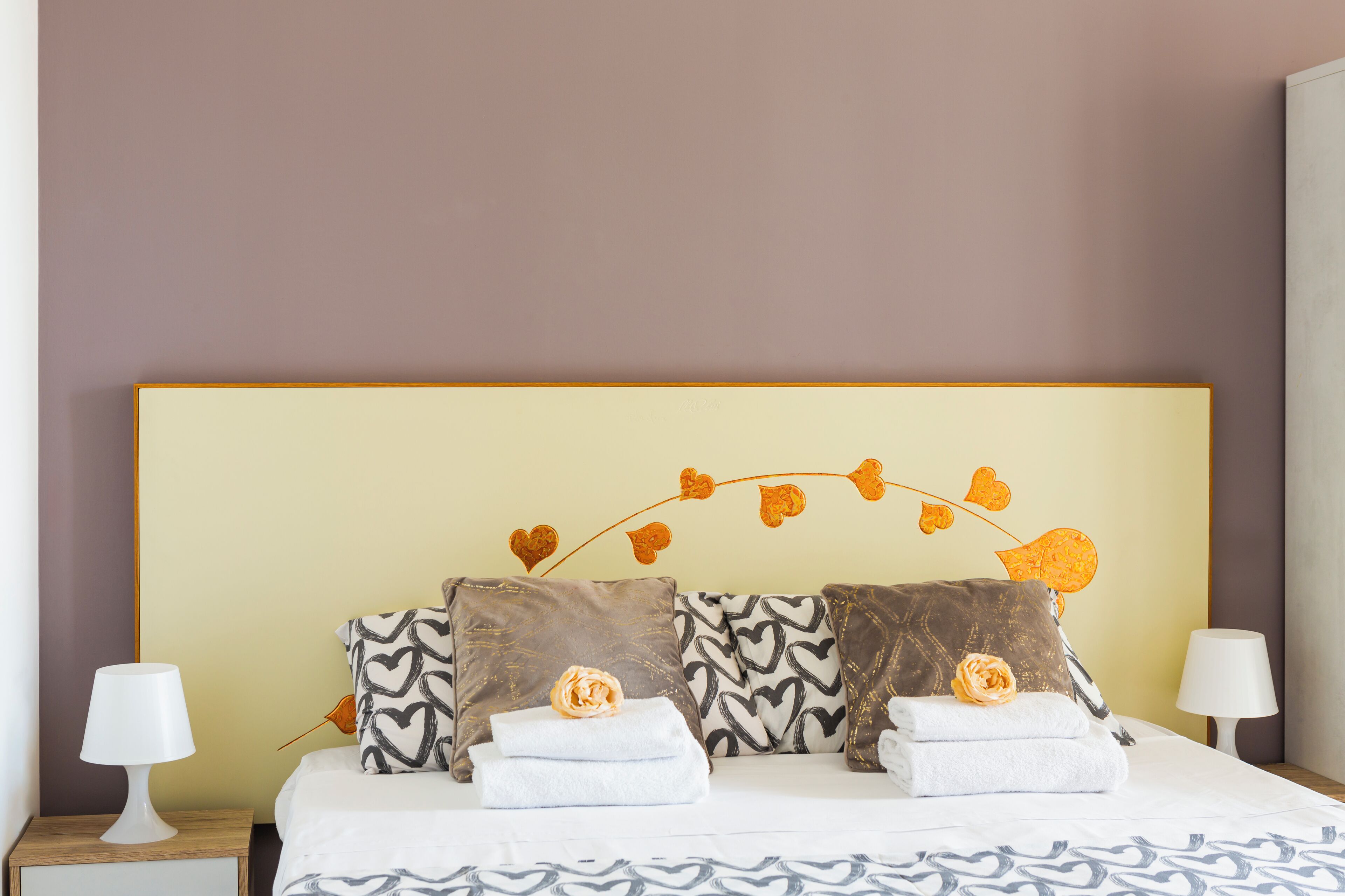 Un lit bien fait, agrémenté d’oreillers à motifs et d’une tête de lit décorative.