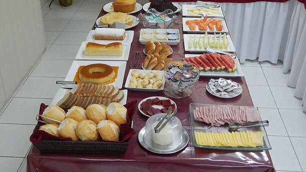 A buffet table with various food items including pastries, fruits, and condiments.