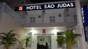 The entrance to Hotel São Judas with a sign above the entrance, a balcony on the upper floor, and potted plants in front.