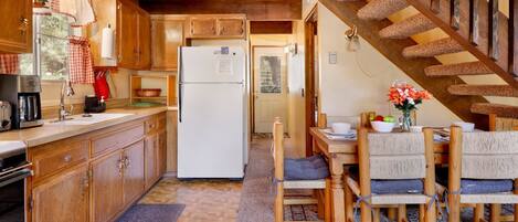 A cozy kitchen with wooden cabinets, a white refrigerator, and a dining area with a wooden table and chairs.