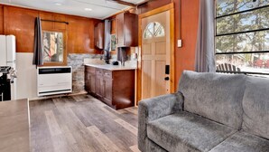 A compact kitchen with wooden cabinets, a built-in oven, and a window overlooking a deck. - Sunset #101 (Big Bear Lake)