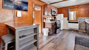 A compact kitchen with wooden cabinetry, a microwave, stove, refrigerator, and a window with a view. - Sunset #101 (Big Bear Lake)