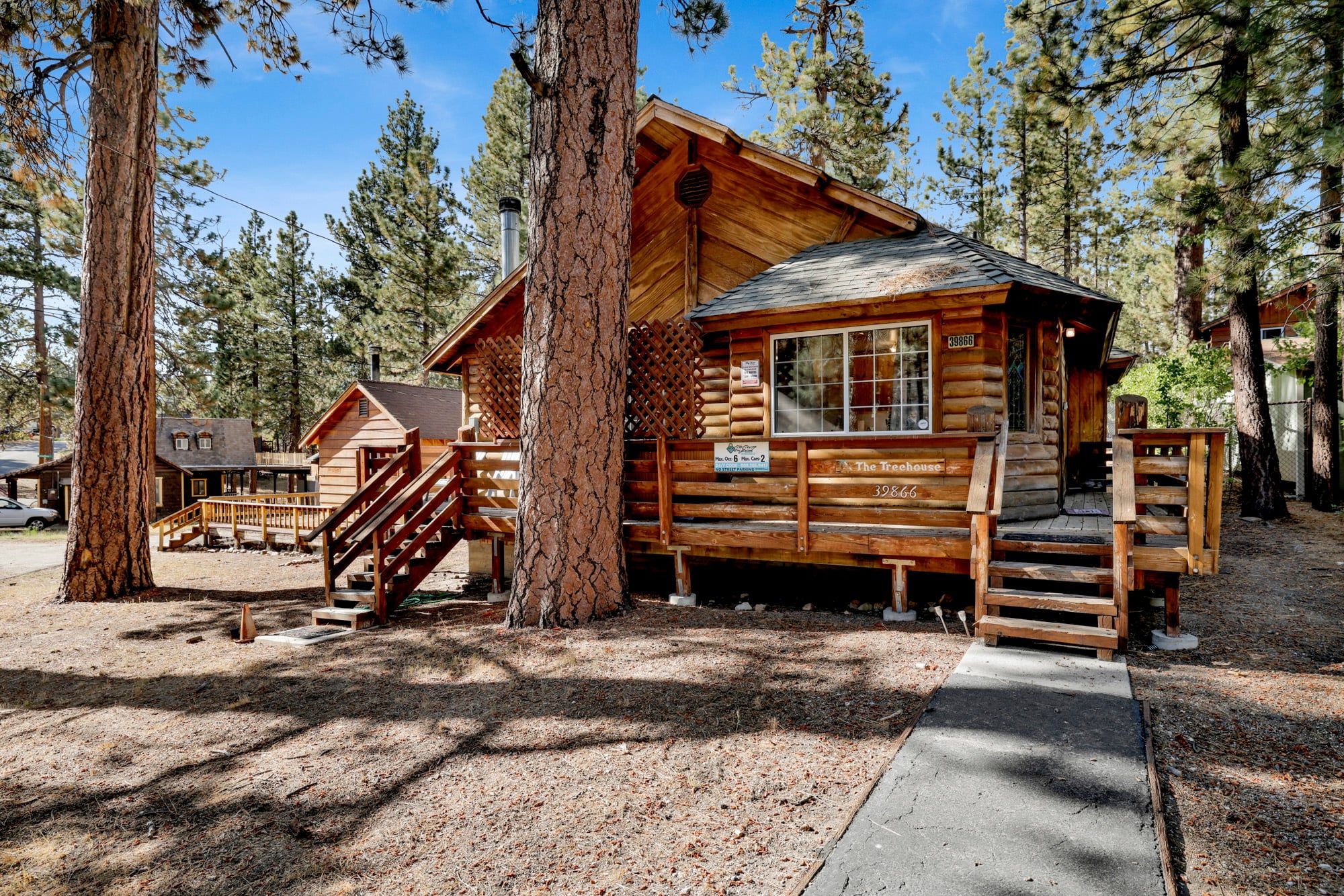 A rustic log cabin with a wooden deck and a staircase leading to the entrance.