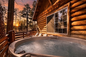 A log cabin with a hot tub, wooden deck, and a large window overlooking a forest. - Forest Treehouse # 1473 (Big Bear Lake)