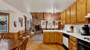 A cozy kitchen with wooden cabinets, a stone fireplace, and a dining area with a wooden table and chairs.