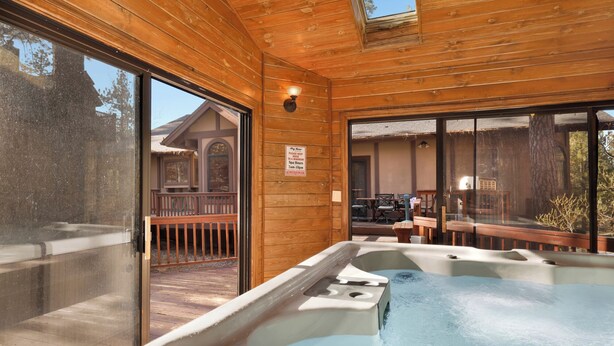 A wooden cabin with a hot tub, large windows, and a deck area. - Four Happy Bears Estate #1277 (Big Bear Lake)