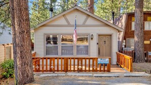 A small, single-story cabin with a wooden deck, a mailbox, and a sign indicating no street parking. - Cedar Pines #1529 (Big Bear Lake)