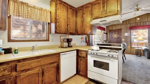 A kitchen with wooden cabinets, a white stove, and a sink. - Cedar Pines #1529 (Big Bear Lake)