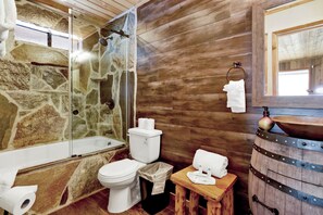 A bathroom with a stone shower enclosure, wooden walls, a white toilet, and a wooden barrel sink. - Pines AND Needles #1454 (Big Bear Lake)