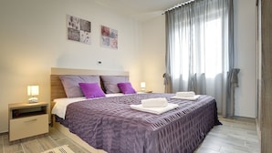 A bedroom with a large bed, two bedside tables, a nightstand, a window with curtains, and wall art. - Villa with private pool, 4 bikes just 590 meters to the pebble beach (Valbandon)