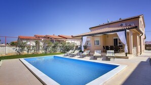 A swimming pool with lounge chairs and a covered patio area. - Villa with private pool, 4 bikes just 590 meters to the pebble beach (Valbandon)