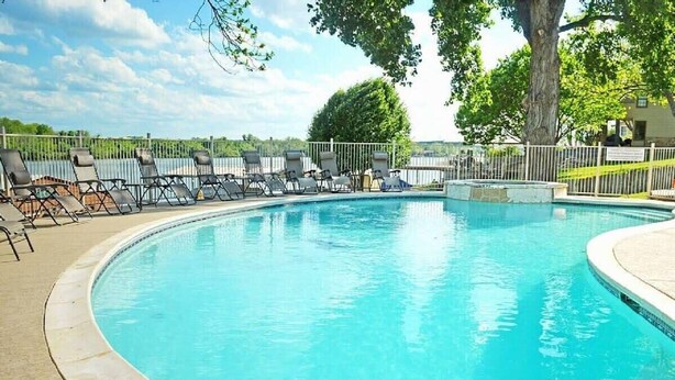 A circular pool with lounge chairs around it, a fenced area, and trees in the background. - Azure 2- Lakefront w/ Shared Pool & Dog Friendly (Kingsland)
