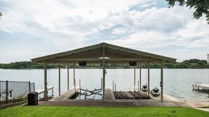 A covered dock with a roof, a grassy area in the foreground, and a body of water in the background. - Azure 2- Lakefront w/ Shared Pool & Dog Friendly (Kingsland)