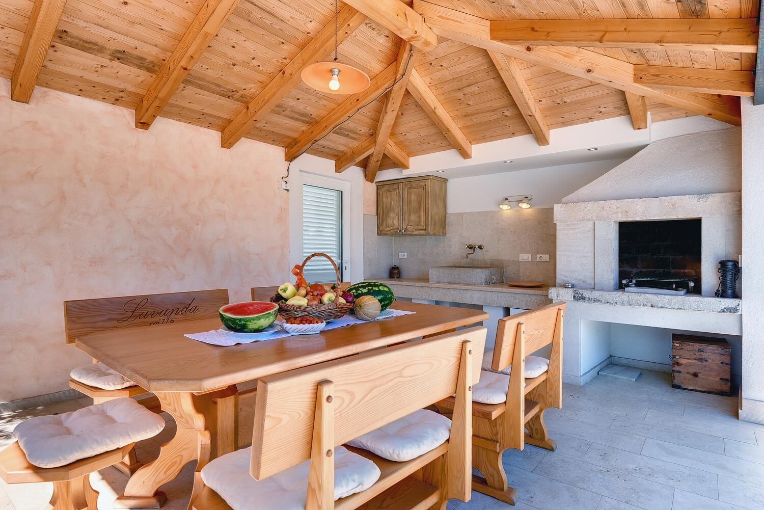 Une cuisine rustique avec une table en bois, des chaises et un panier de fruits.
