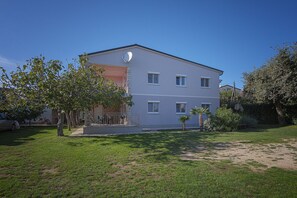 Um edifício de vários andares com telhado plano, antena parabólica e varanda.