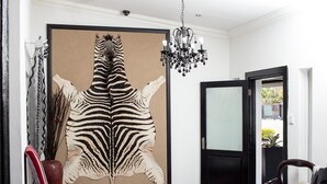 A room with a large zebra skin artwork on the wall, a chandelier, and a door leading to another area. - Big Ben Lodge (Polokwane)