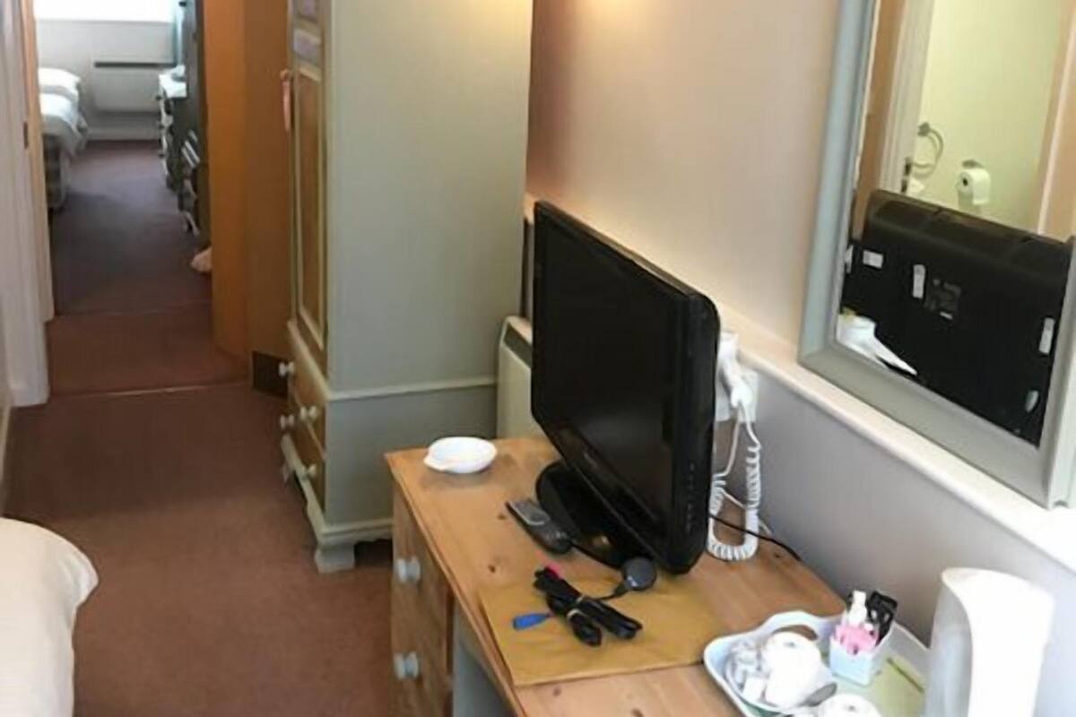 Ein Hotelzimmer mit einem Holztisch, einem Fernseher, einem Spiegel und einer Kommode.