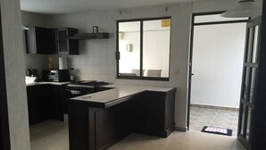 Une cuisine moderne dotée d’un îlot central, de meubles de rangement noirs et d’une grande fenêtre.