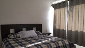 Un lit avec une couvre-lit à carreaux, un oreiller blanc et une tête de lit sombre.