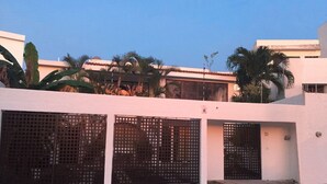 Un bâtiment à l’extérieur blanc, doté d’une entrée fermée par un portail et sur lequel on peut voir le chiffre « 13 » peint sur le mur.