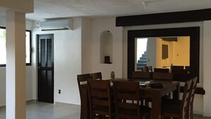 Un coin repas avec une table et des chaises, une porte et un escalier en arrière-plan.
