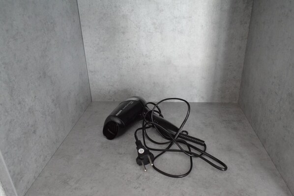 A hair dryer with a power cord on a plain, light-colored floor. - Garni Hotel 31 (Spisska Nova Ves)