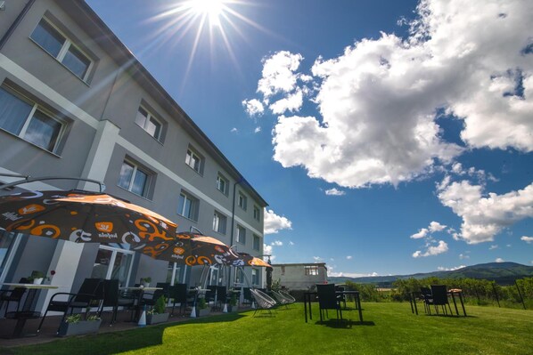 Un hôtel doté d’une terrasse, sous un ciel dégagé, avec une chaîne de montagnes en toile de fond.