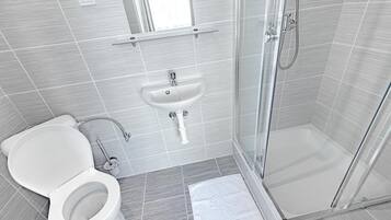 Une salle de bain moderne équipée de toilettes, d’un lavabo et d’une douche.