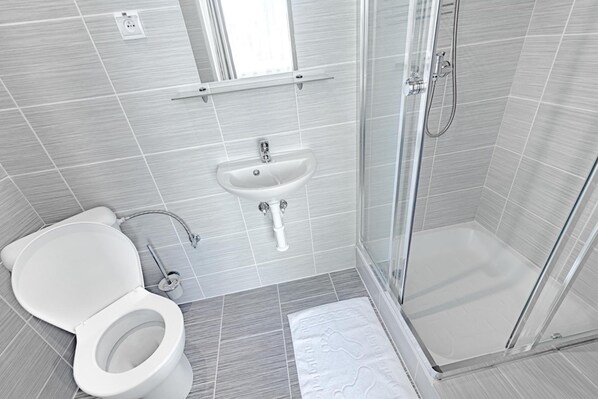 Ein modernes Badezimmer mit Toilette, Waschbecken und Dusche.