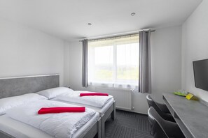 A hotel room with two beds, a desk, a chair, a television, and a window with curtains. - Garni Hotel 31 (Spisska Nova Ves)