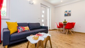 Ein modernes Wohnzimmer mit einer Couch, einem kleinen Esstisch und roten Stühlen.