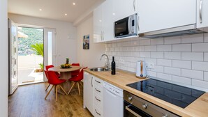 Eine moderne Küche mit weißen Schränken, einer schwarzen Mikrowelle, einem Geschirrspüler und einer Holz Arbeitsplatte.