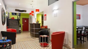 A lobby with a reception desk, red chairs, a staircase, and a patterned floor. - Enzo Hotels Contrexéville (Contrexéville)