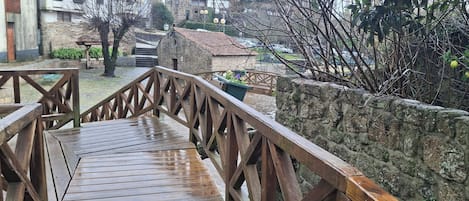 A wooden bridge leading to a stone wall with a potted plant.