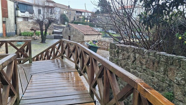A wooden bridge leading to a stone wall with a potted plant.