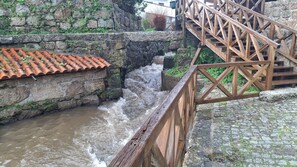 A stone wall with a tiled roof, a wooden staircase, and a flowing water channel.