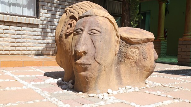 A stone sculpture in an outdoor setting with a brick wall and tiled flooring. - Roba Monakedi Guest Lodge (Mahikeng)
