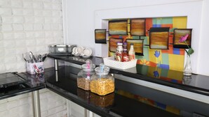 A kitchen counter with a black countertop, stainless steel appliances, and a colorful wall art piece. - Roba Monakedi Guest Lodge (Mahikeng)