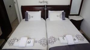 A double bed with a wooden headboard, two pillows, and a bedside table with a lamp. - Roba Monakedi Guest Lodge (Mahikeng)