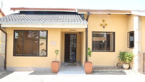 A building with a reception area, two potted plants, and a tiled roof. - Roba Monakedi Guest Lodge (Mahikeng)