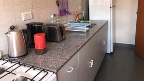 Una cocina equipada con estufa a gas, hervidor, tostadora y refrigerador.