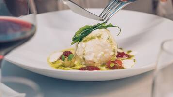 Un plat blanc amb una culleradeta de gelat decorat amb una fulla i microverds, acompanyat d'una forquilla i un ganivet.