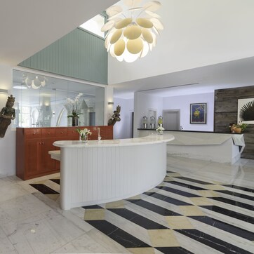 A modern kitchen with a central island, a large window, and a decorative ceiling light.