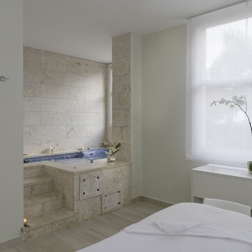 A modern bathroom with a bathtub, a sink, and a window with a view of palm trees.